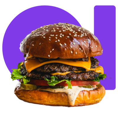 A loaded burger with a sesame seed bun, melted cheese, lettuce, tomato, and sauce.