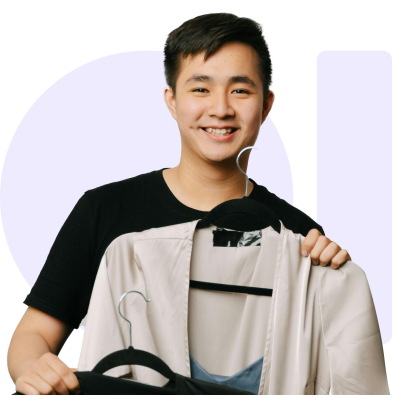 Young person smiling, holding beige jacket and black clothing on hangers.