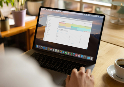 Business owner reviewing customer segments on a MacBook Pro, with a coffee cup on the desk beside them.
