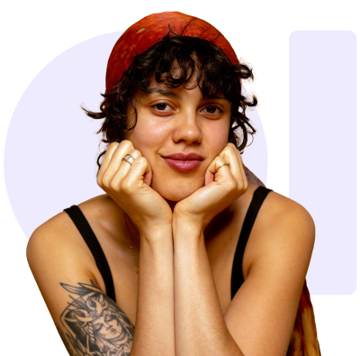 A smiling young woman with curly hair and a red cap resting her chin on her hands.