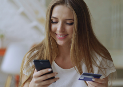 Customer showing a smartphone with a successful payment confirmation while paying at a cafe counter.