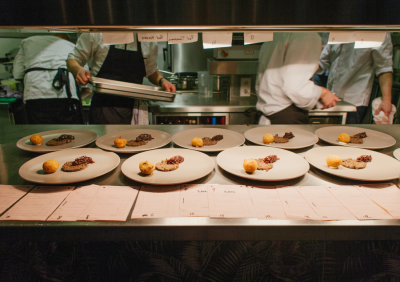 Multiple plated dishes lined up on a restaurant kitchen pass ready for service.