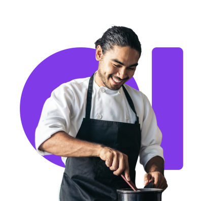 A smiling chef in a white jacket and black apron stirring a pot.